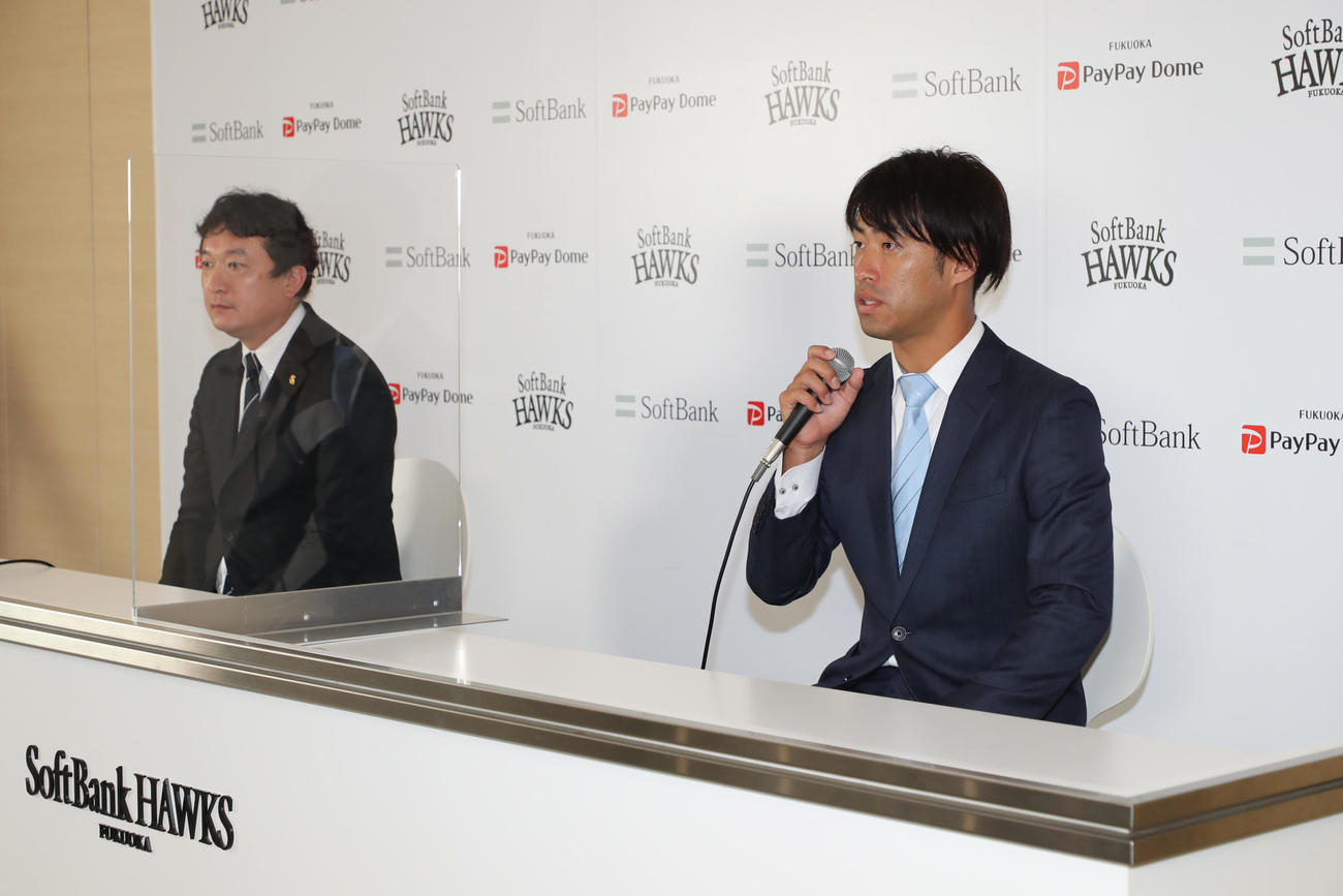 入団会見で抱負を語る秋吉亮投手。左は三笠取締役GM（外部提供）