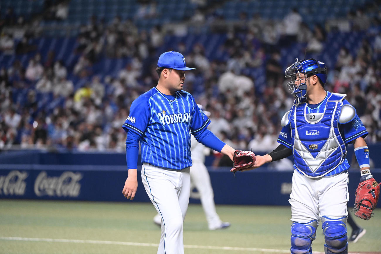 中日対DeNA 8回終了、嶺井とタッチを交わしベンチへ戻るDeNA3番手で登板した伊勢（左）（撮影・森本幸一）