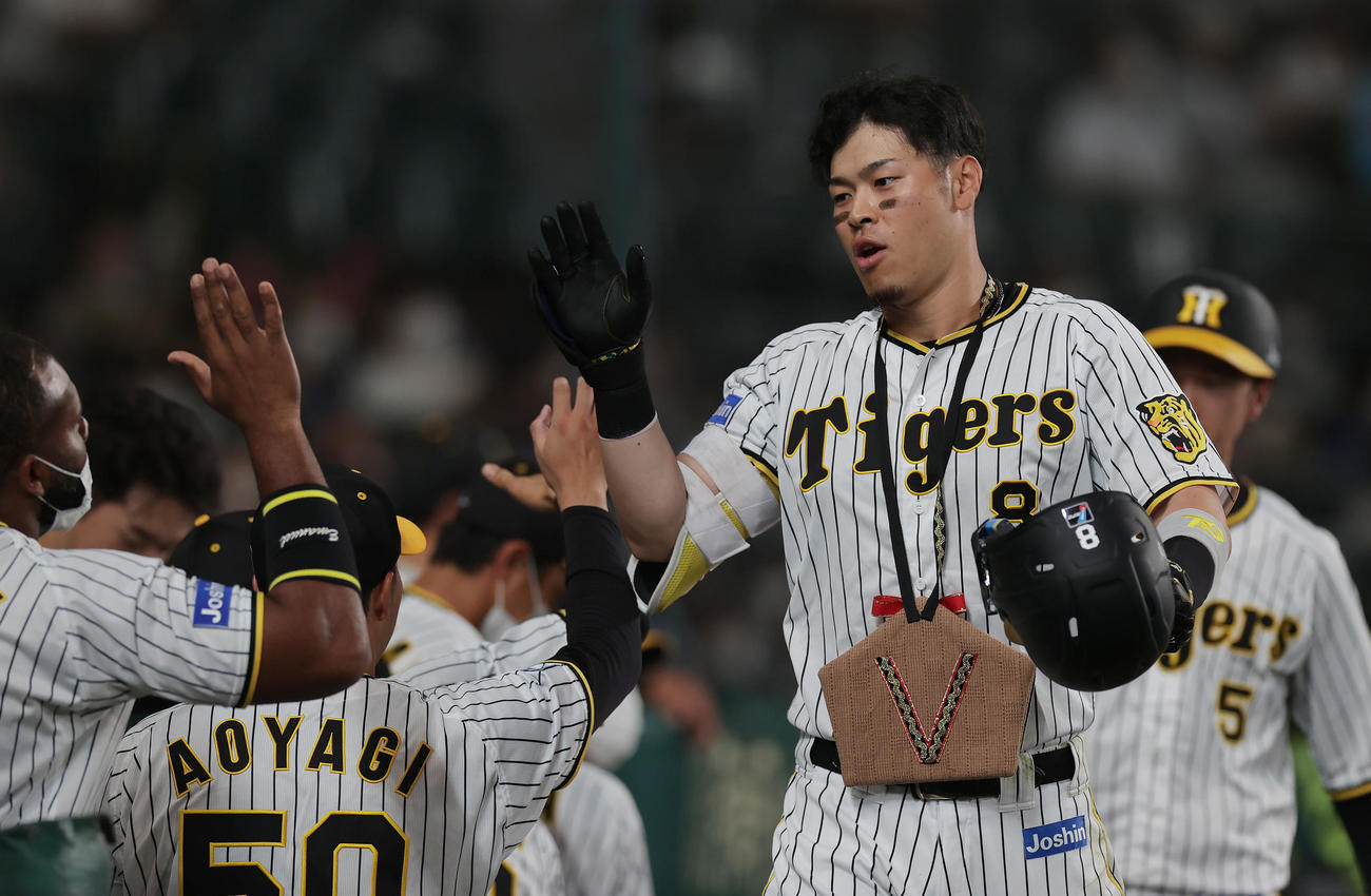 阪神対DeNA 6回裏阪神2死二塁、中越え2点本塁打を放ち、ナインに迎えられる佐藤輝（撮影・前田充）