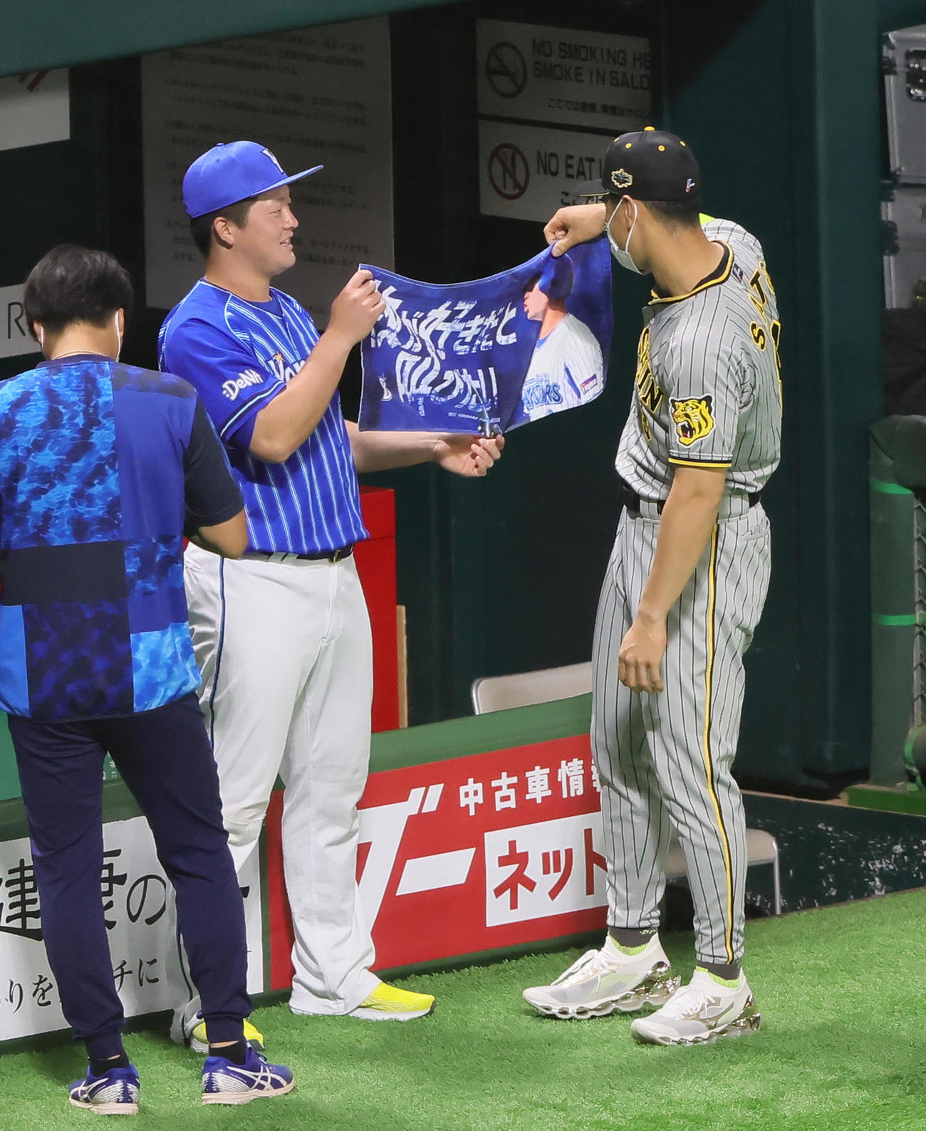 試合前、DeNA牧（左）のタオルを見つめる阪神佐藤輝（撮影・足立雅史）