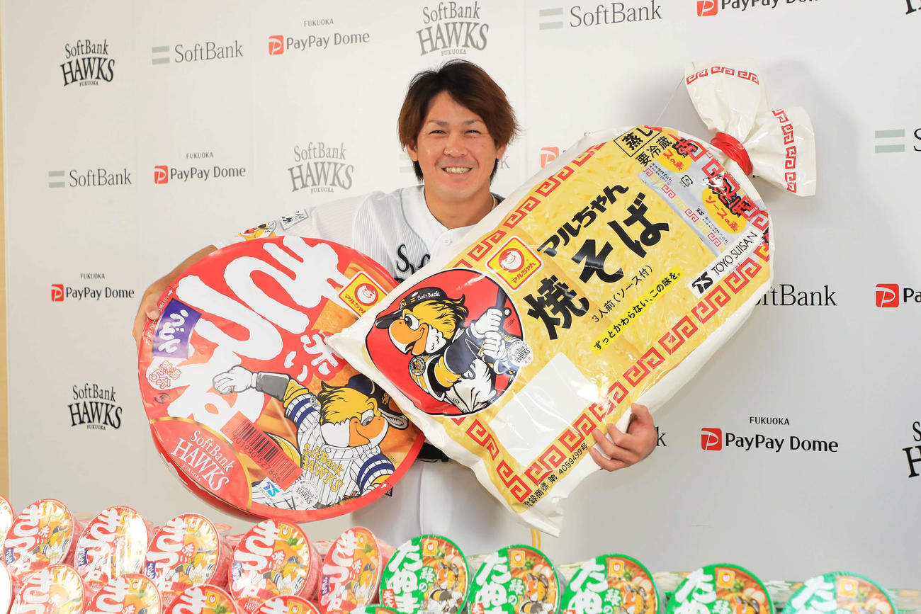 巨大な「マルちゃん　赤いきつねうどん」と「マルちゃん　焼そば3人前」を手に笑顔のソフトバンク甲斐拓也（球団提供）