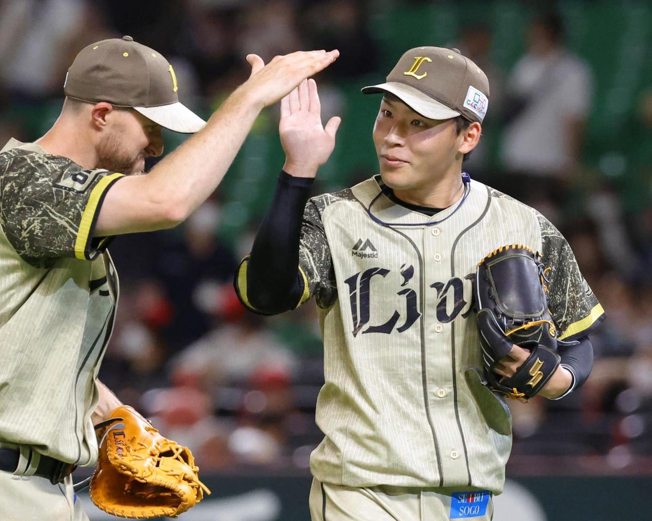 プロ初セーブを挙げジャンセン（左）とタッチを交わす西武水上（共同）