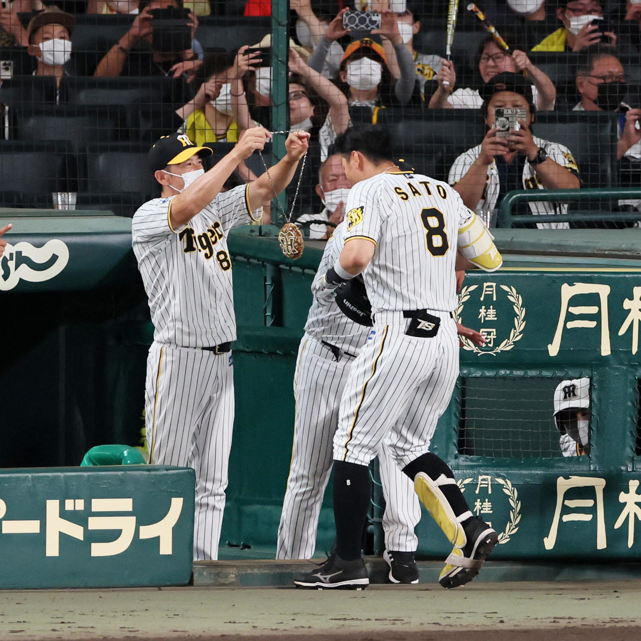 阪神対ヤクルト　5回裏阪神無死、佐藤輝は左越え本塁打を放ち矢野監督（左）からメダルをかけてもらう（撮影・加藤哉）