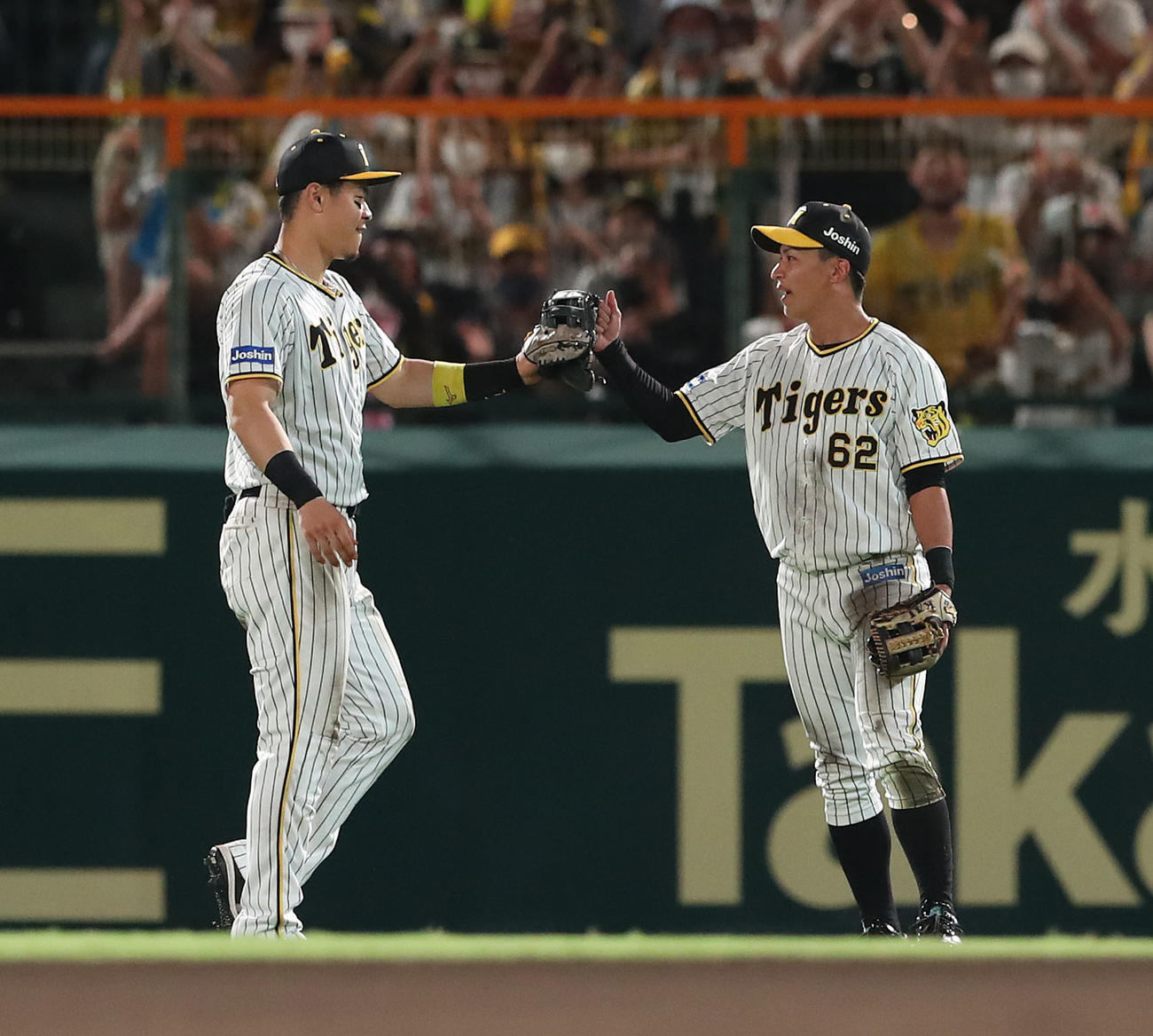 阪神対ヤクルト　10回表1死、長岡の打球を背面キャッチした植田（右）は佐藤輝とタッチを交わす（撮影・白石智彦）
