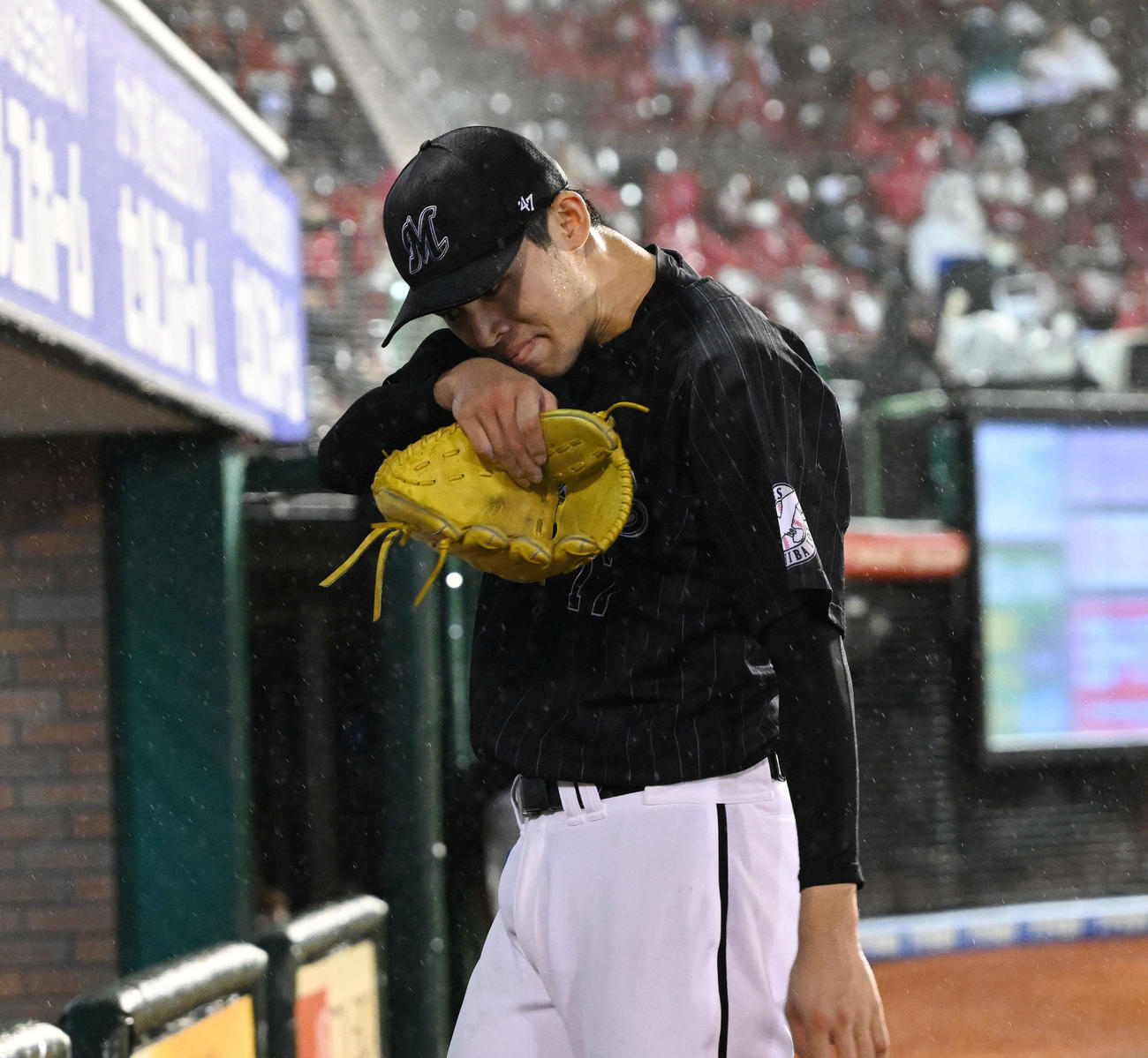 楽天対ロッテ　6回途中、降板したロッテ佐々木朗は雨にぬれた顔をぬぐいながらベンチへ引き揚げる（撮影・滝沢徹郎）