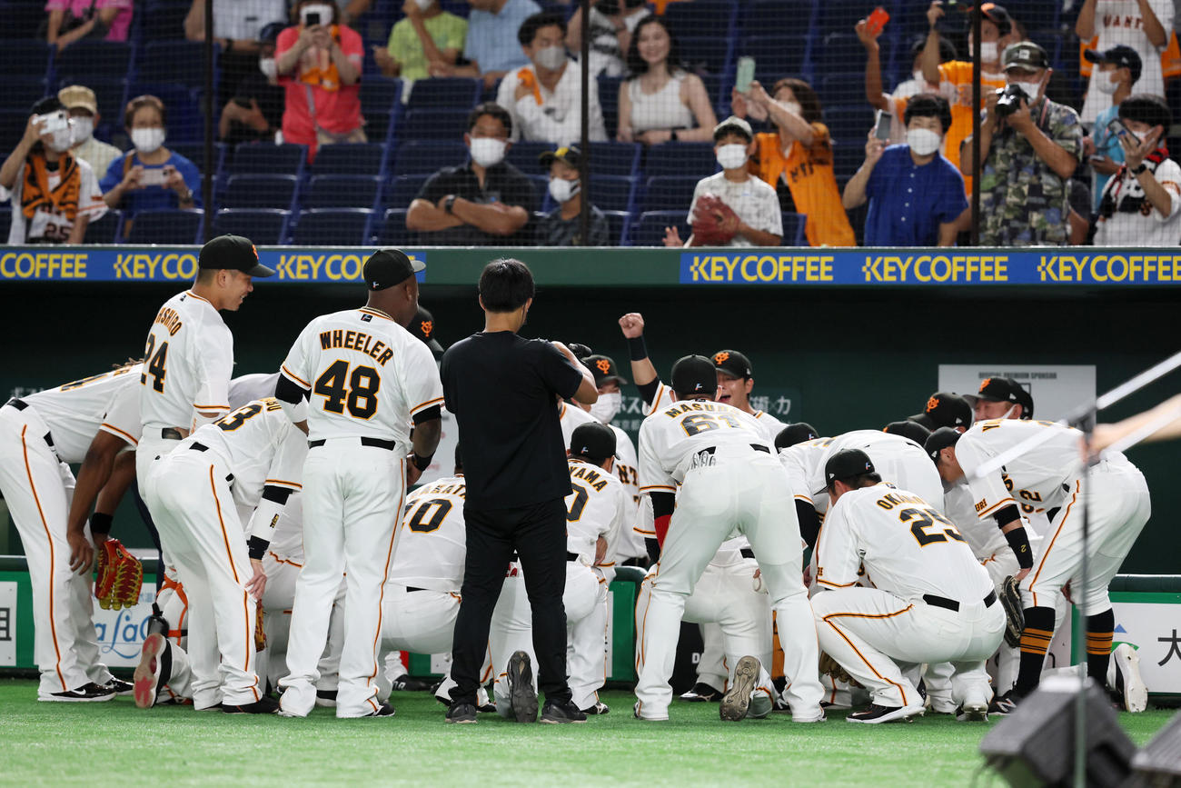 巨人対阪神　中心で湯浅が岡本和の顔写真プリントを手に試合前の円陣を組んだ巨人ナイン（撮影・加藤哉）