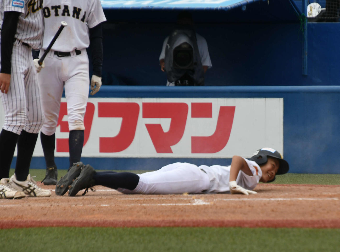 4回表、好判断で二塁から生還した札幌大谷・寺町は滑ったままニッコリ