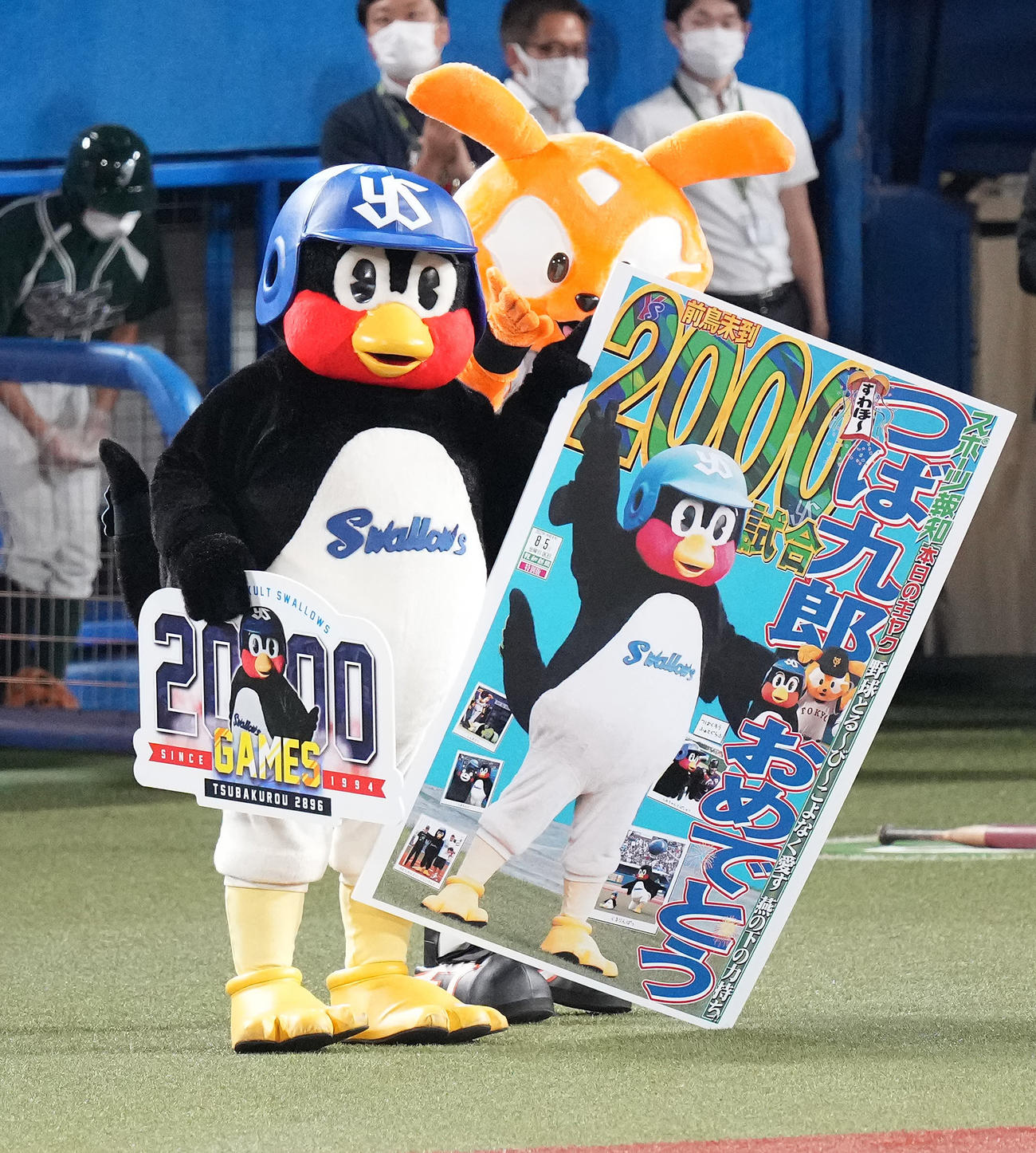 ヤクルト対巨人　主催2000試合出場を達成しパネルを手にするつば九郎。後ろはジャビット（撮影・鈴木みどり）