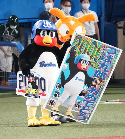 ヤクルト対巨人 主催2000試合出場を達成しパネルを手にするつば九郎。後ろはジャビット(撮影・鈴木みどり)