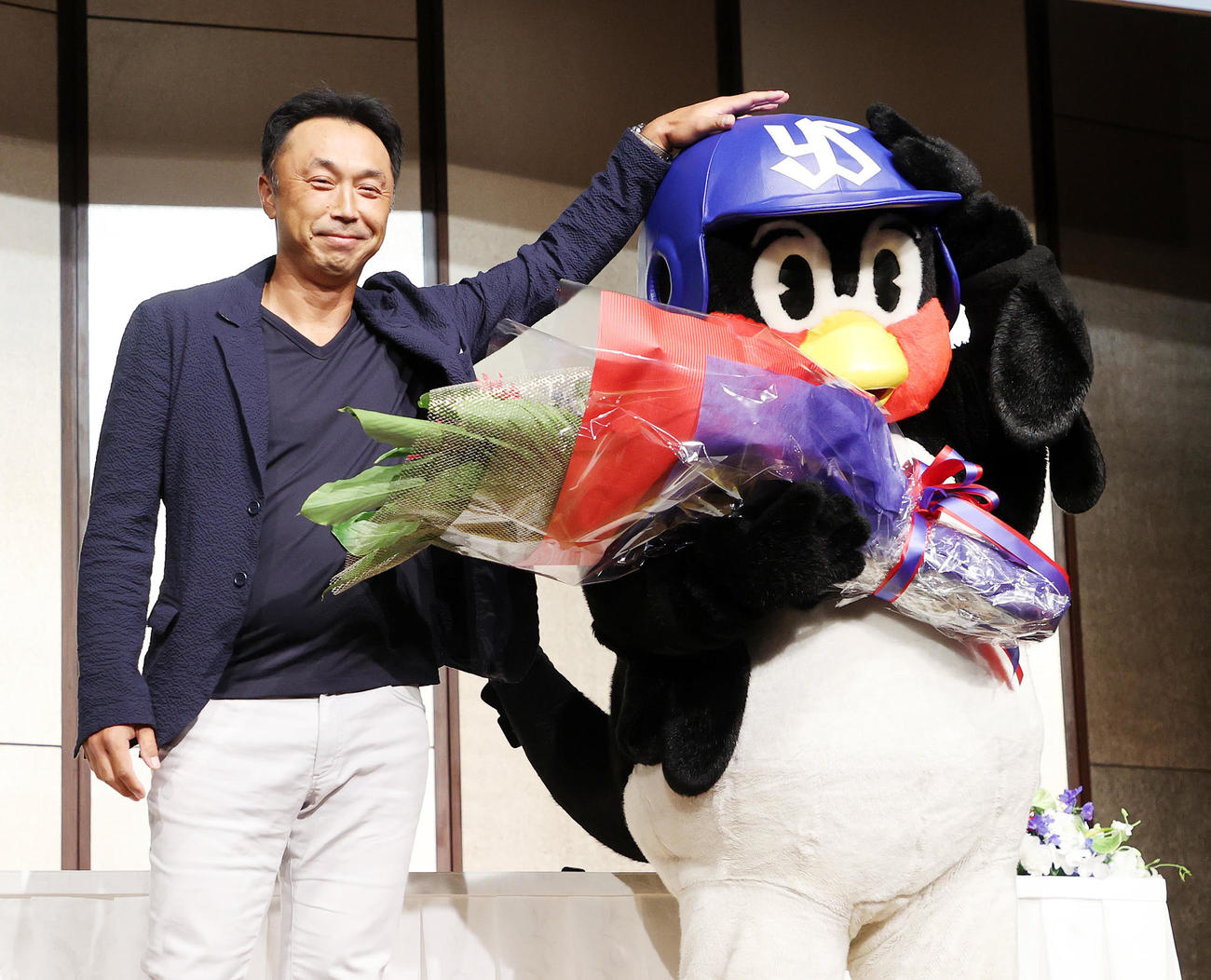 サプライズゲストの宮本慎也氏（左）から花束を受け取り写真に納まるつば九郎（撮影・鈴木正人）