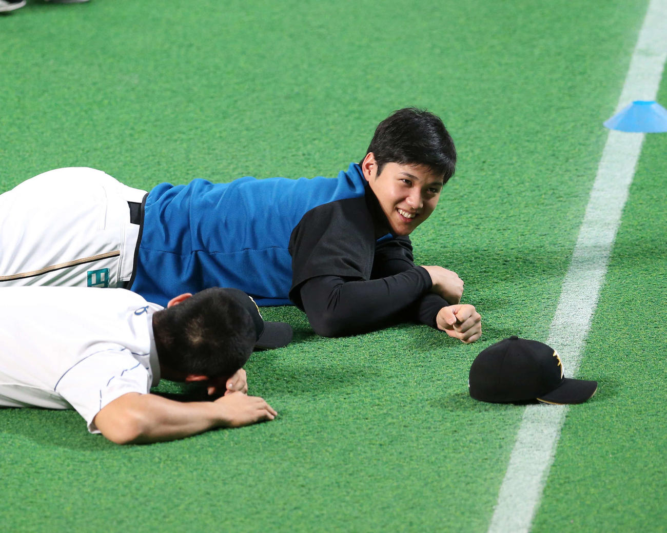 練習開始前、グラウンドに寝転びリラックスする日本ハム時代の大谷（中央）。手前は近藤（2016年10月4日撮影）