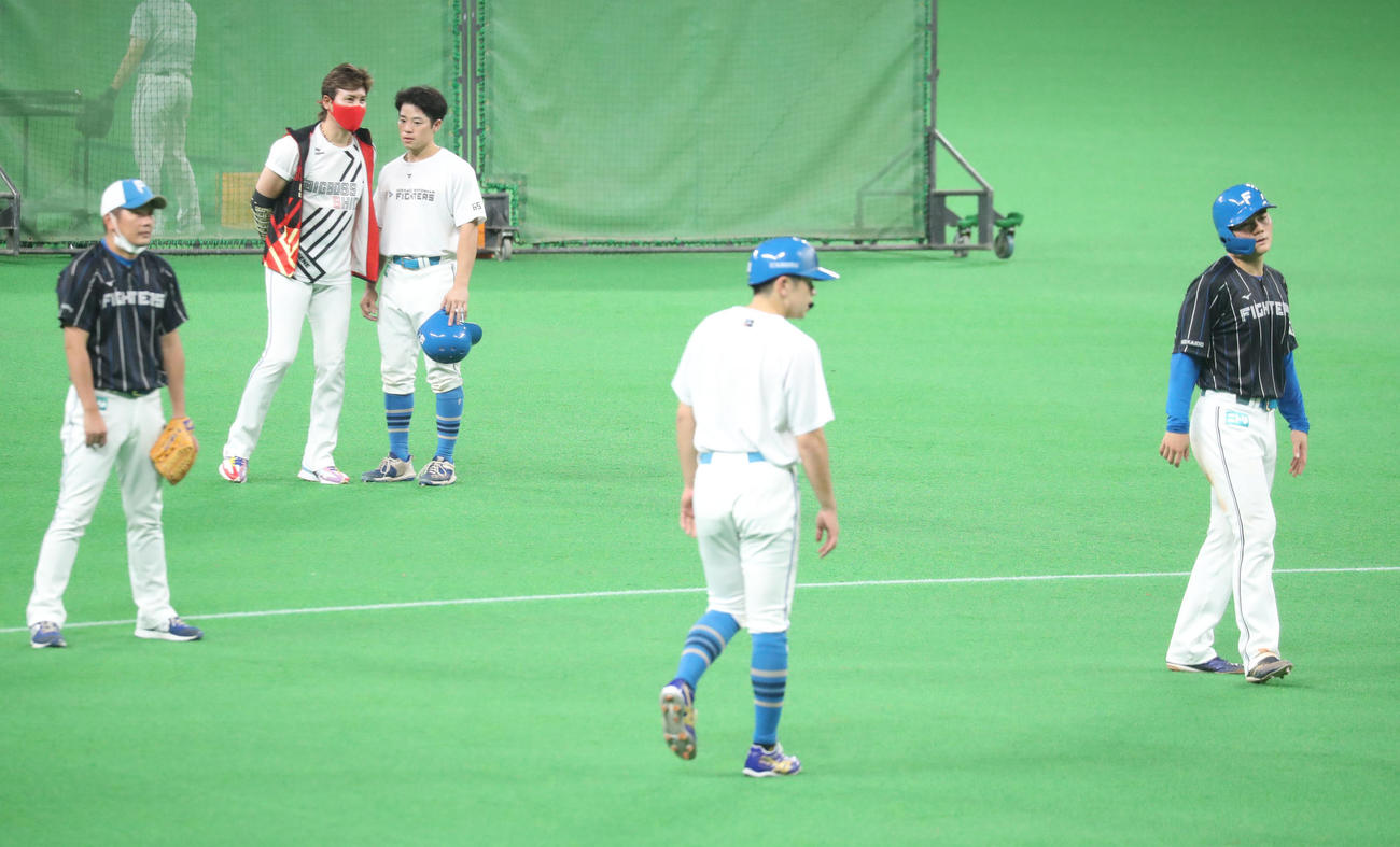 日本ハム対西武　試合前、新庄監督（左後方）は梅林と会話する。右は走塁練習をする清宮（撮影・佐藤翔太）