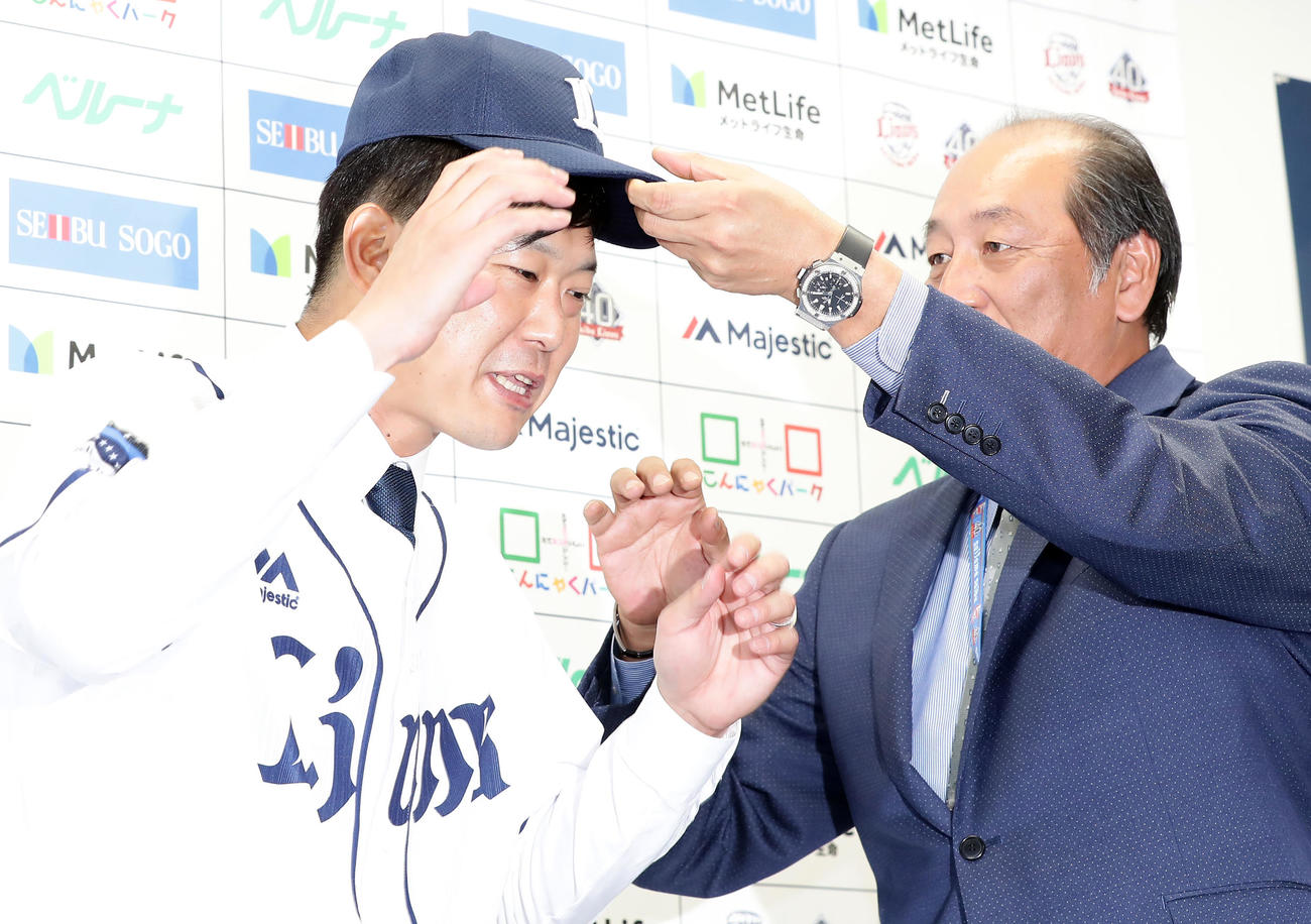 西武入団会見に臨んだ内海（左）はユニホームを着用し渡辺SDから帽子をかぶせてもらう（2018年12月21日撮影）