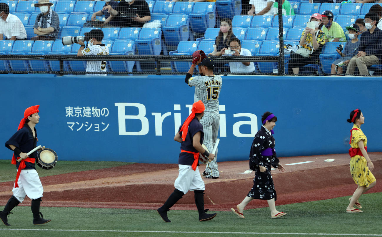 ヤクルト対阪神　試合前、エイサーを披露したグループのメンバーが退場する中、ブルペンで投球練習をする阪神先発の西純（後方）（撮影・狩俣裕三）