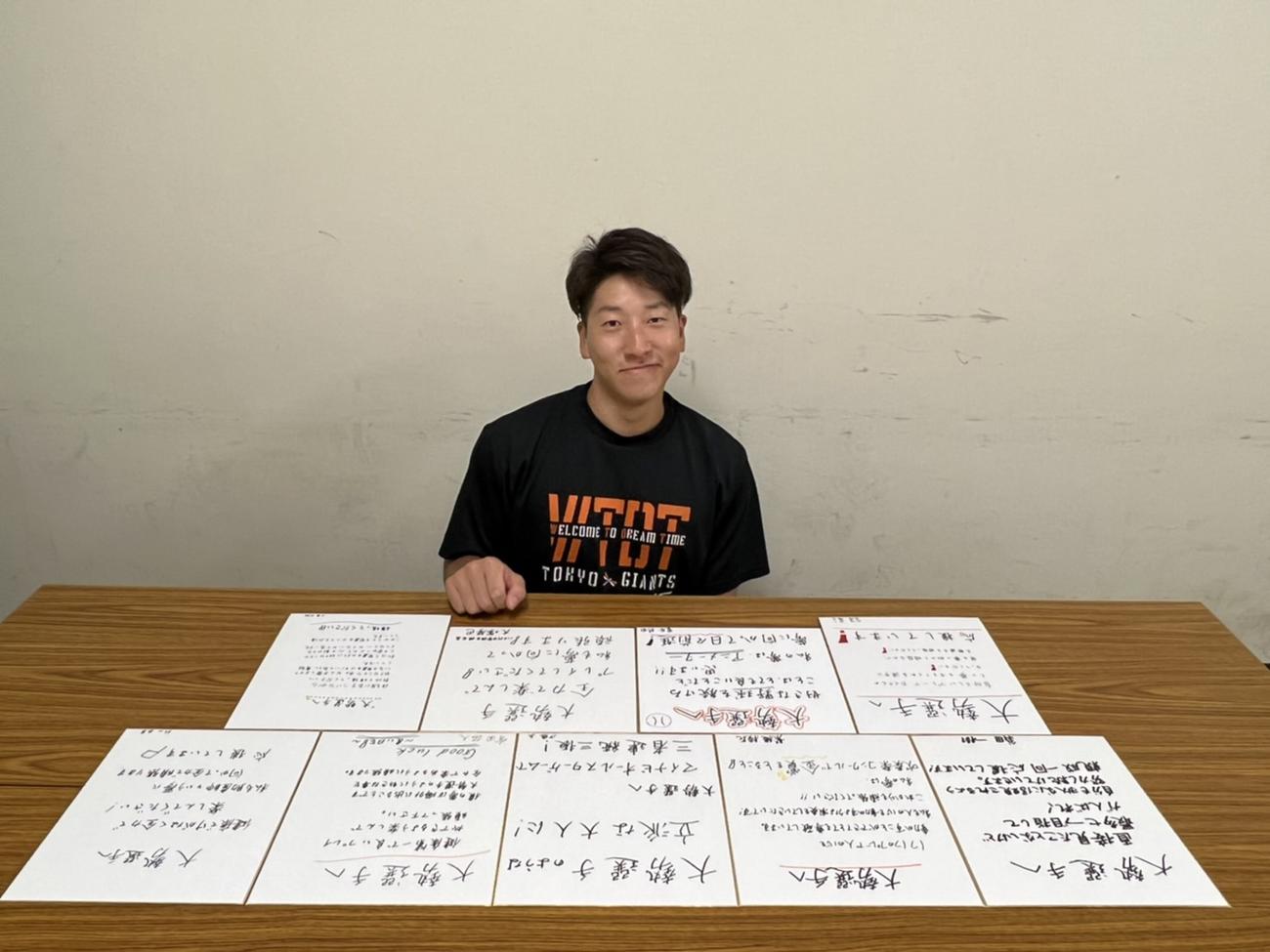 母校・八千代中の後輩たちからのメッセージが書かれた色紙を前に笑顔を見せる巨人大勢（球団提供）