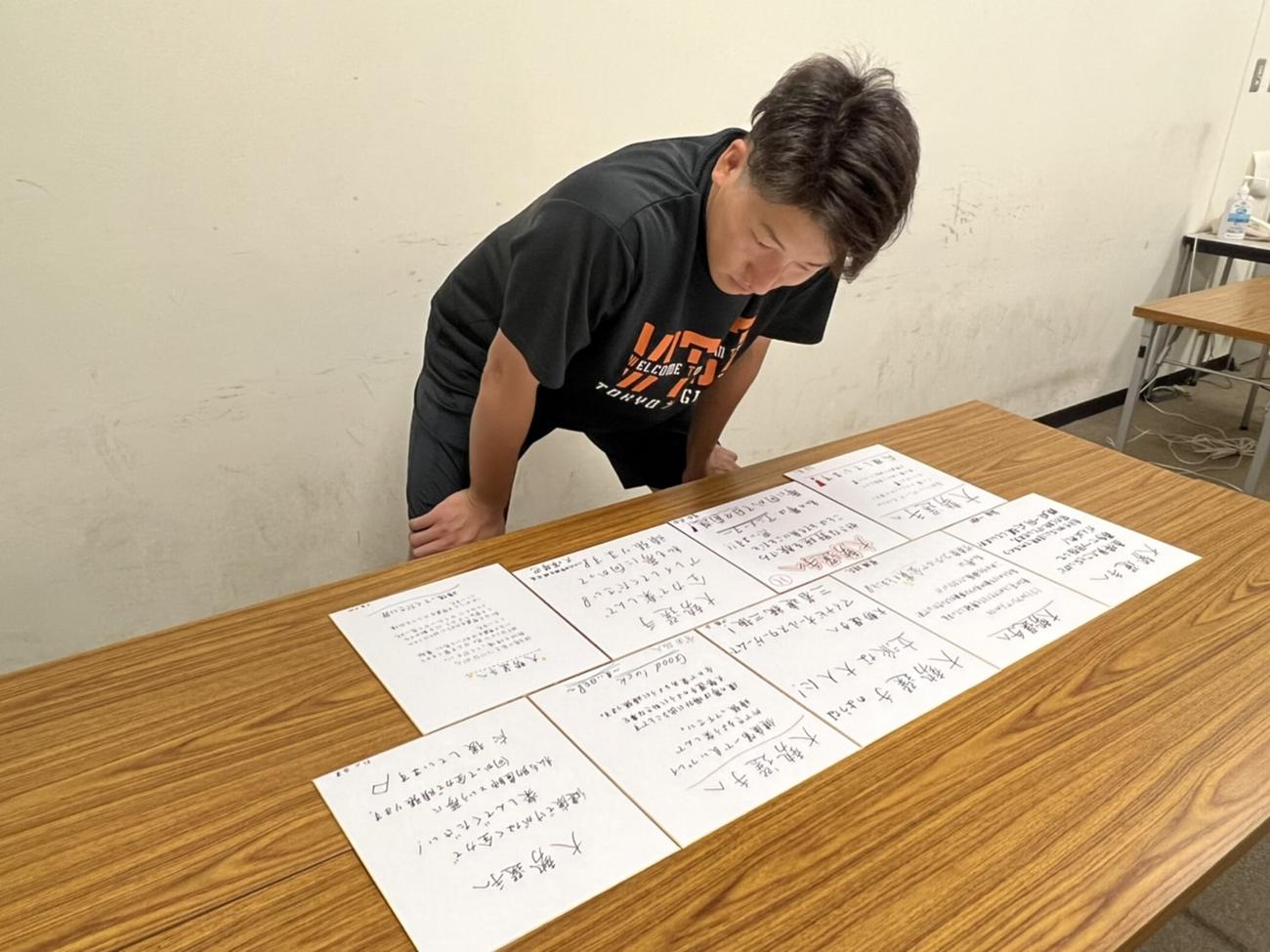 母校・八千代中の後輩たちのメッセージが書かれた色紙をじっくり見る巨人大勢（球団提供）