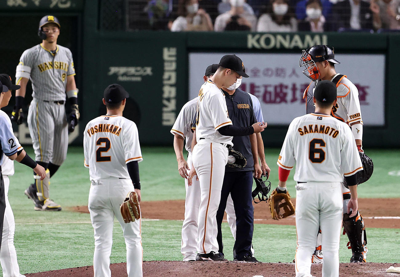 巨人対阪神　7回表阪神無死二塁、打者佐藤輝（後方）に2球投げた後、右手指先の異常で降板する山崎伊（撮影・狩俣裕三）