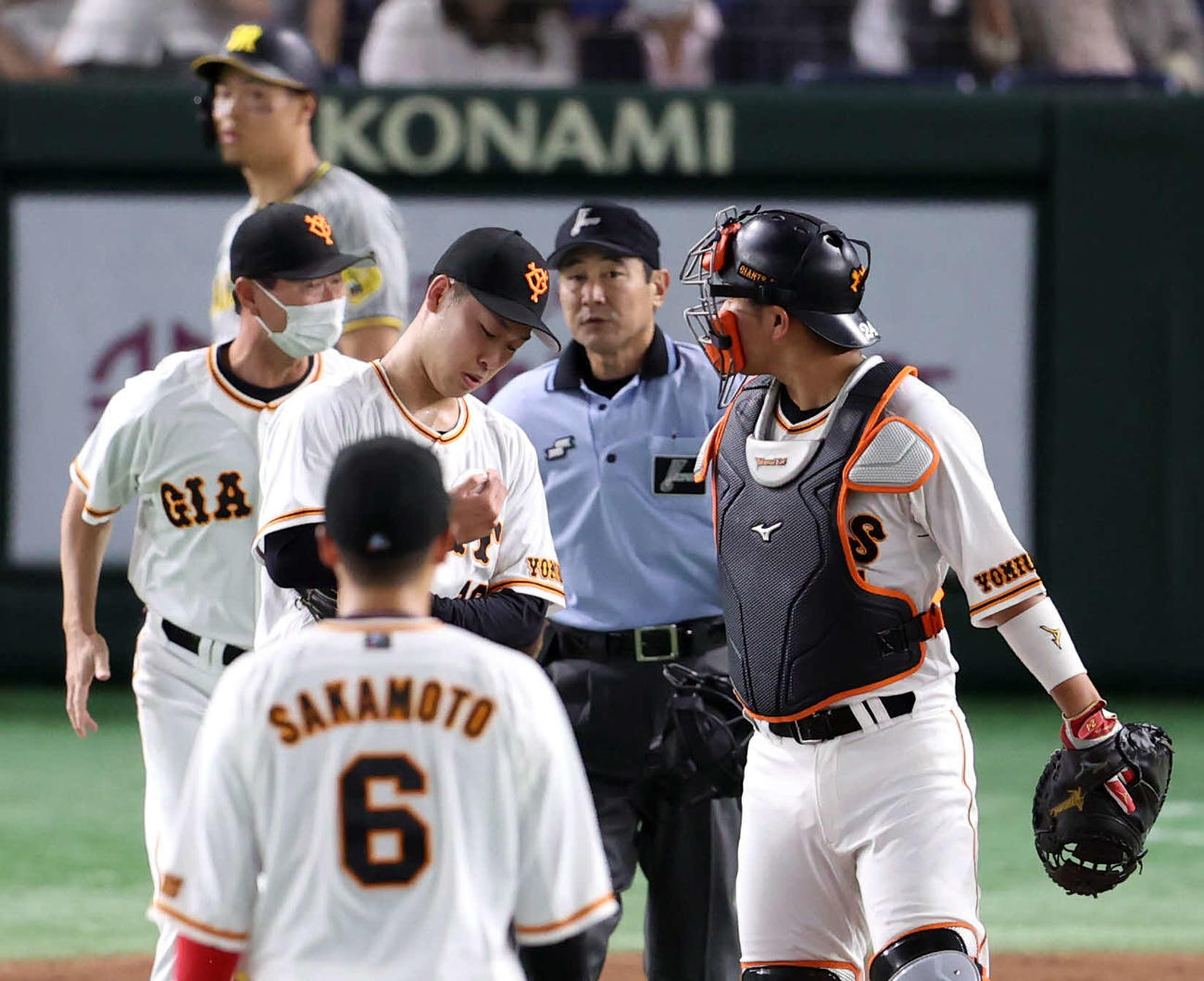 巨人対阪神　7回表阪神無死二塁、打者佐藤輝（後方）に1球投げた後、右手指先の異常で降板する山崎伊（右から3人目）（撮影・狩俣裕三）