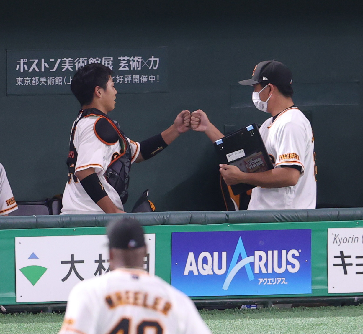 巨人対阪神　1回表を終え、実松バッテリーコーチ（右）とタッチを交わす喜多（撮影・狩俣裕三）