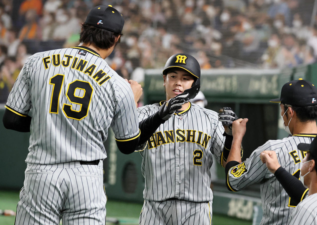 巨人対阪神　4回表阪神2死一、三塁、三塁走者梅野は島田のセーフティースクイズで生還し藤浪(左）らナインとタッチする（撮影・加藤哉）