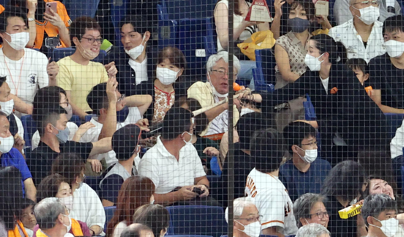 巨人対阪神　1回表阪神1死一、三塁、一塁側ベンチ上の客席まで飛んできた佐藤輝のバットをスタッフに返すファン（撮影・狩俣裕三）