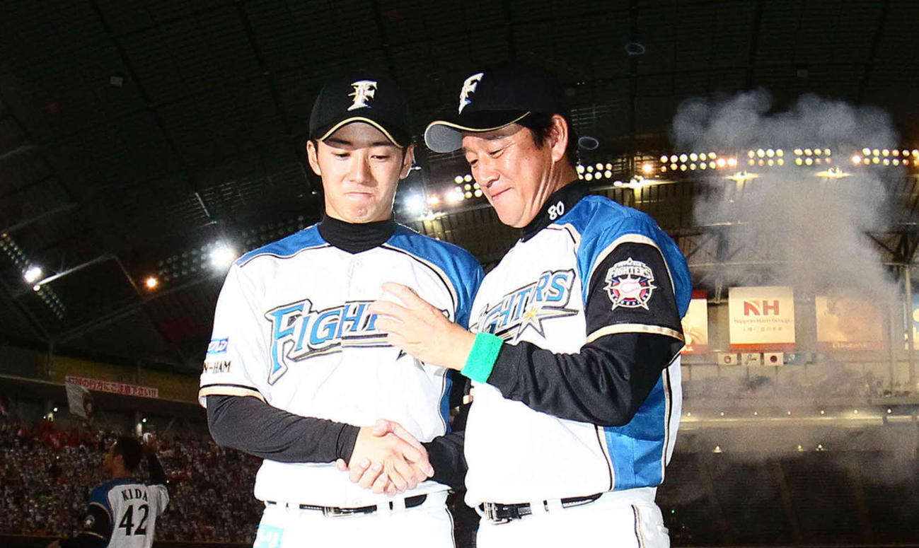 開幕戦で初完投勝利を飾った斎藤（左）は初勝利の栗山監督とウイニングボールを見つめる