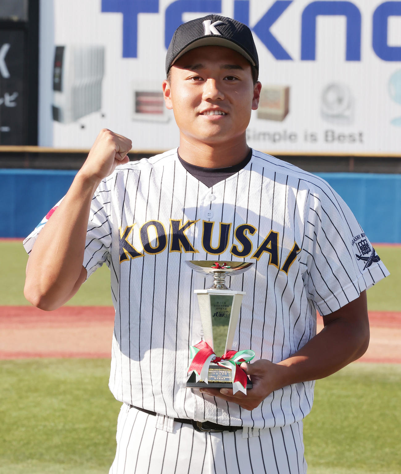 首位打者賞を受賞し、トロフィーを手にガッツポーズの東日本国際大・上崎（撮影・野上伸悟）