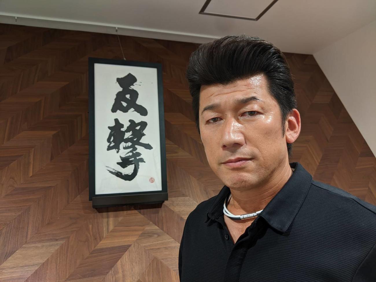 監督室に飾られる「反撃」と書かれた書と写真に納まるDeNA三浦監督（球団提供）