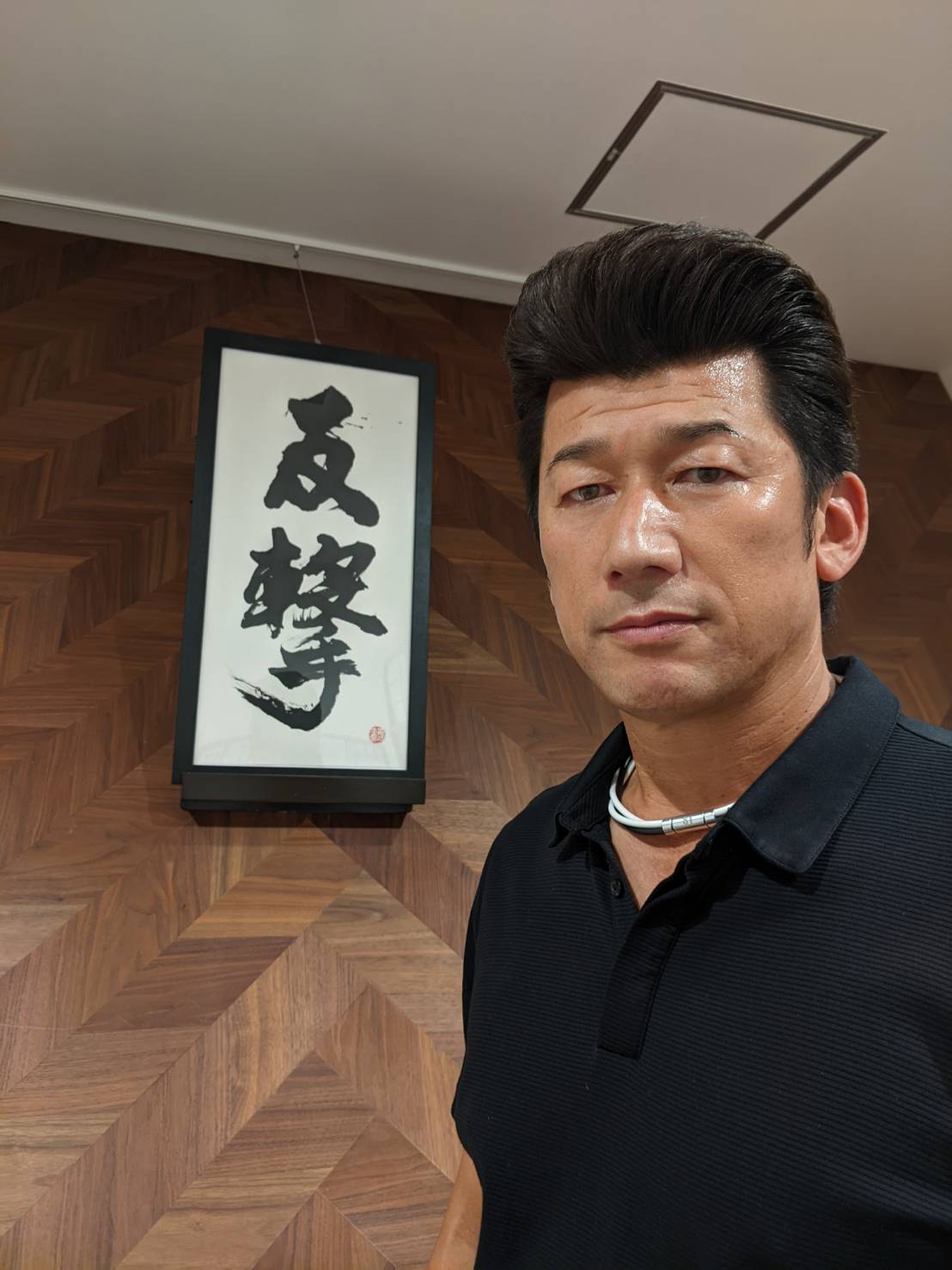 監督室に飾られる「反撃」と書かれた書と写真に納まるDeNA三浦監督（球団提供）