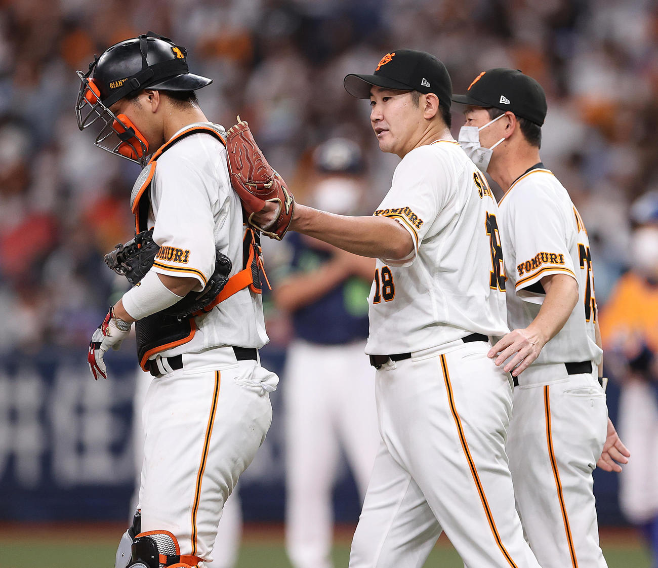 巨人対ヤクルト　6回表、大城（左）の背中をポンとたたく菅野（中央）。右は桑田投手チーフコーチ（撮影・狩俣裕三）