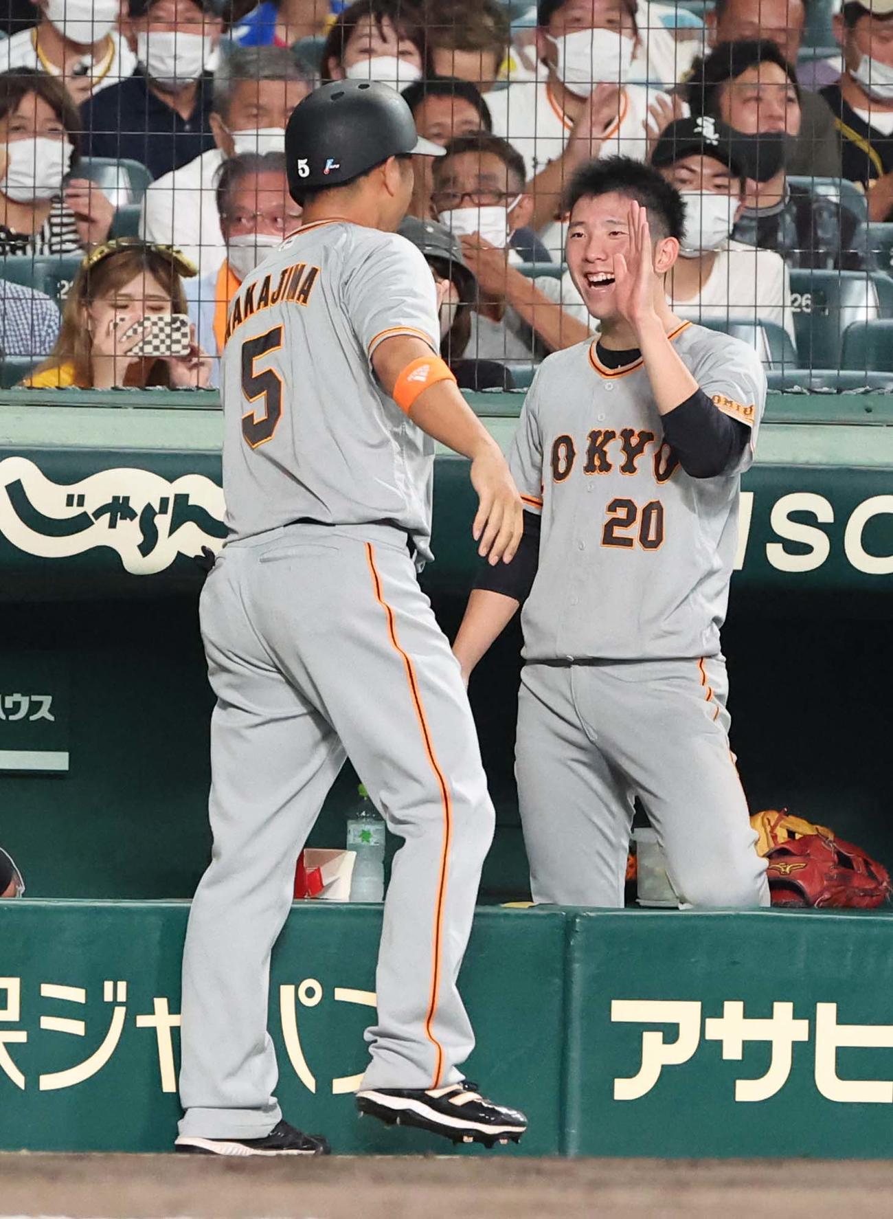 阪神対巨人　9回表巨人2死一、二塁、同点適時打を放った中島（左）を笑顔で出迎える戸郷（撮影・上田博志）