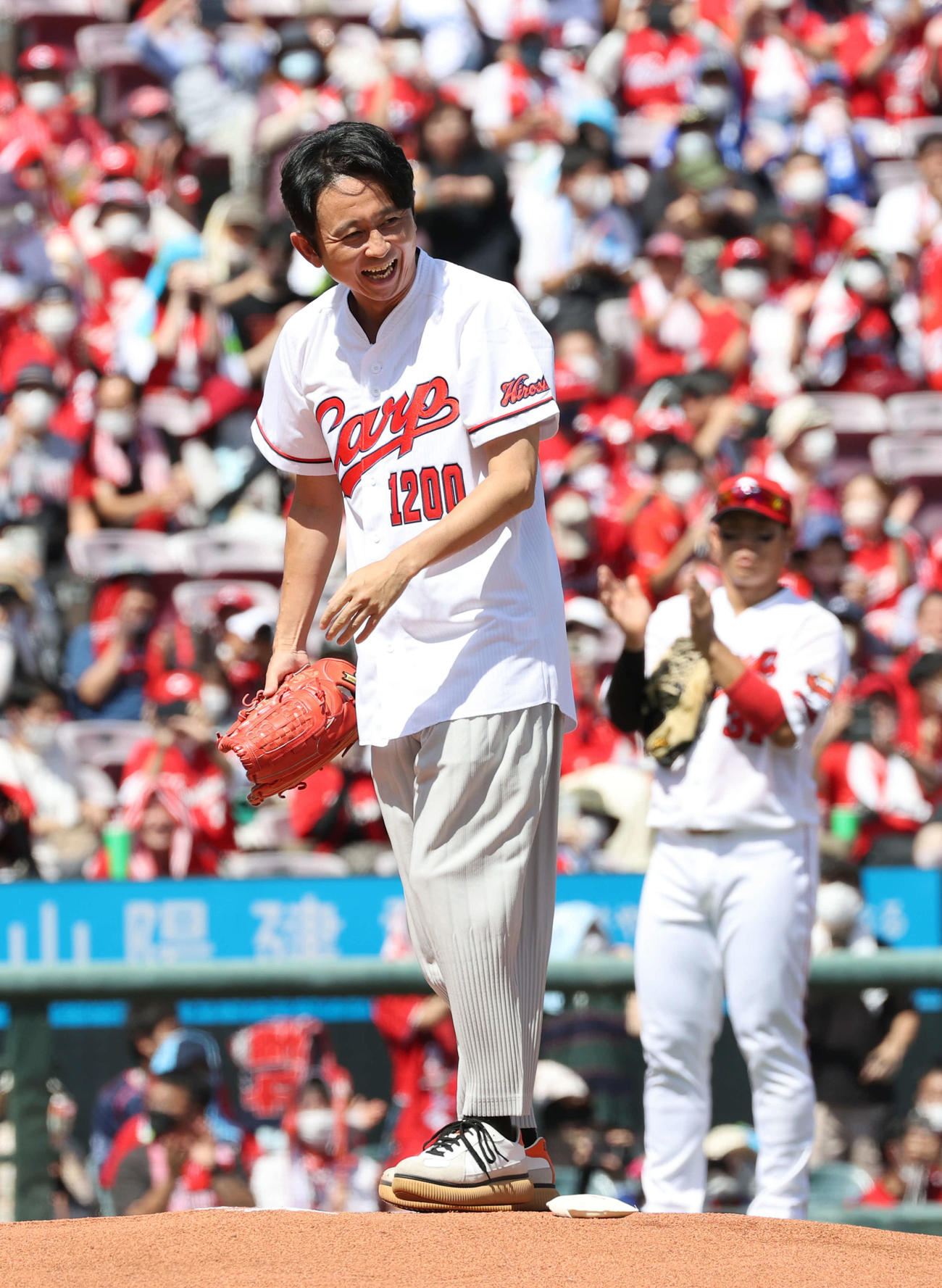 広島対DeNA　始球式で投球し、笑顔をみせる有吉弘行。右は坂倉（撮影・加藤孝規）