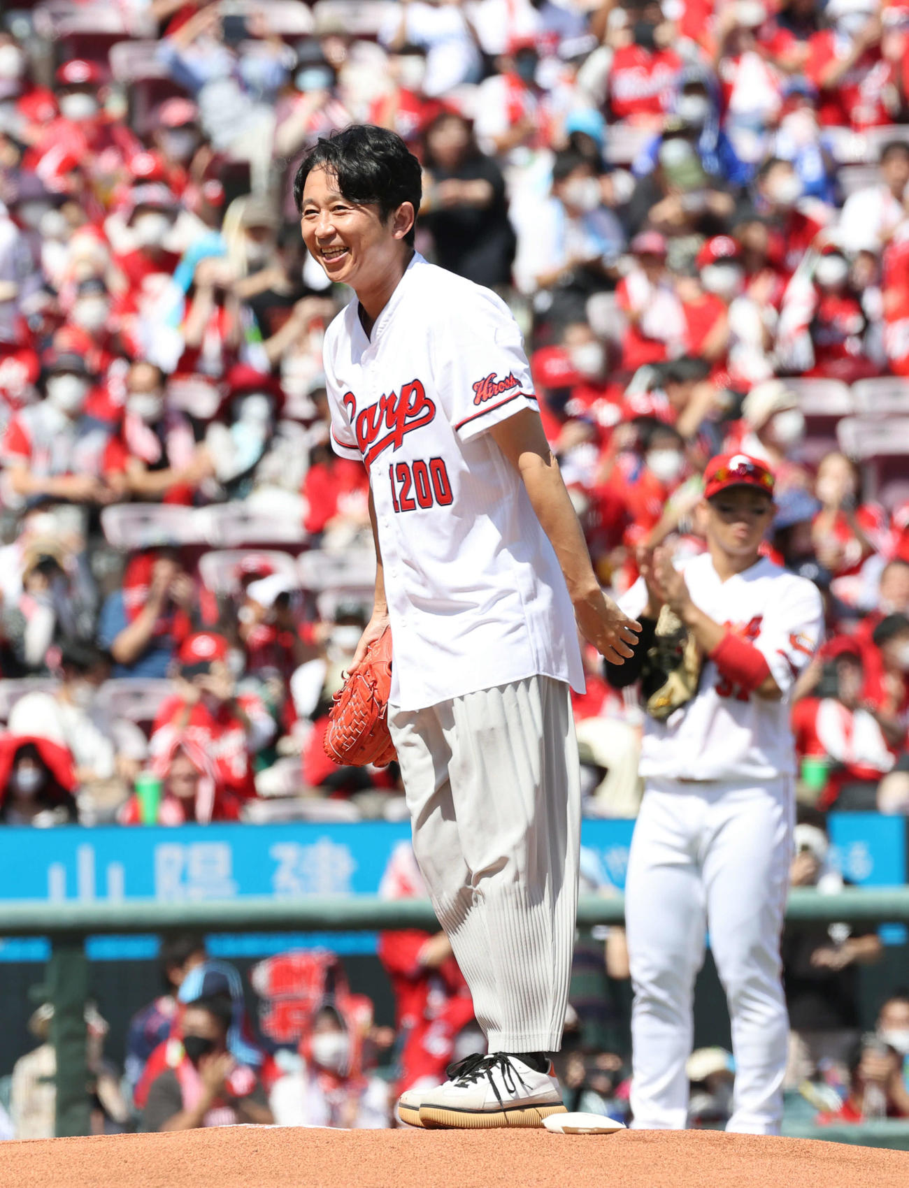 広島対DeNA　始球式で投球し、笑顔をみせる有吉弘行。右は坂倉（撮影・加藤孝規）