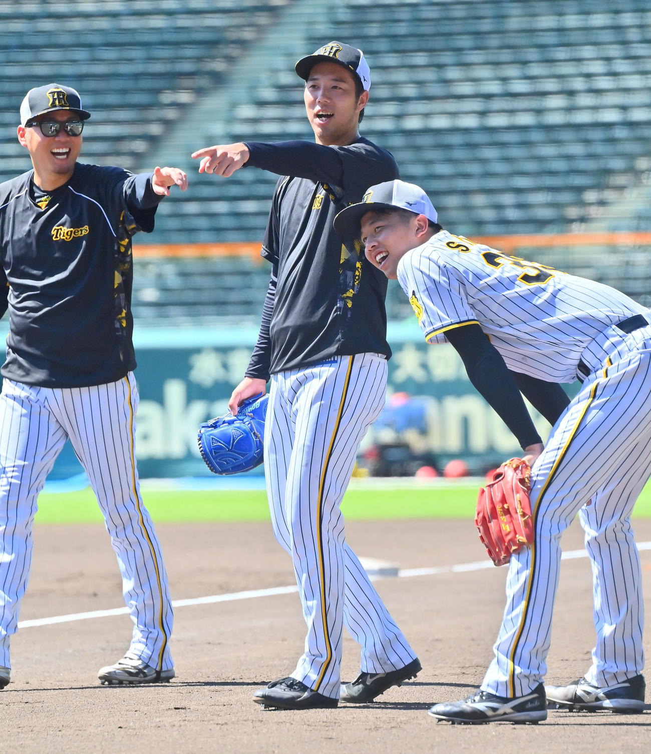 明るい表情で投内連携を行う阪神青柳、左は西勇、右は才木（撮影・和賀正仁）