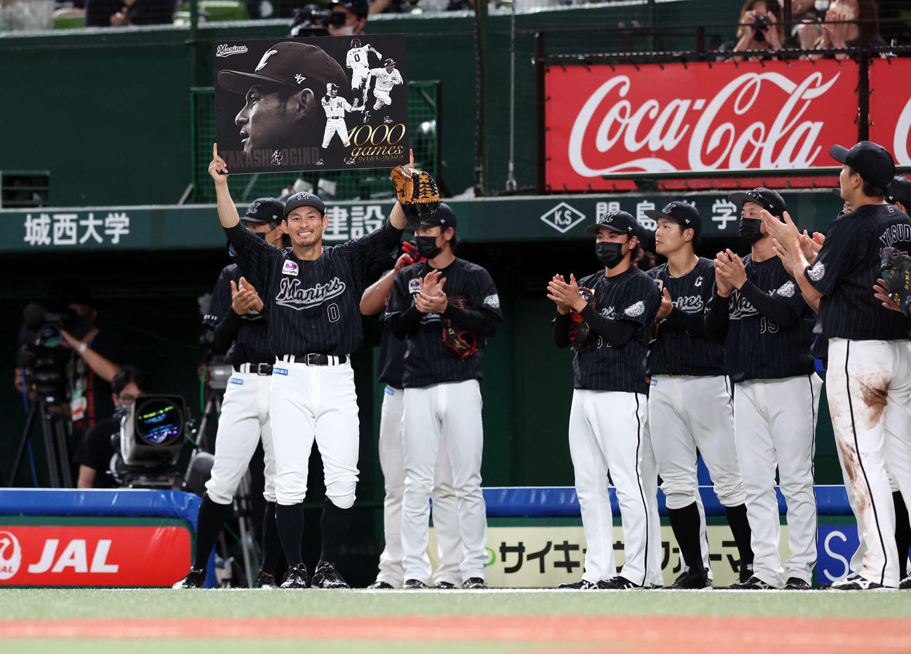 西武対ロッテ　5回裏西武の攻撃後、1000試合出場を達成したロッテ荻野（左）はボードを掲げて笑顔を見せる（撮影・浅見桂子）