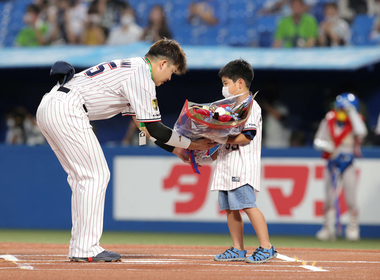 史上最年少でプロ通算150号本塁打を達成した村上（左）はファンから花束を受け取る（撮影・井上学）