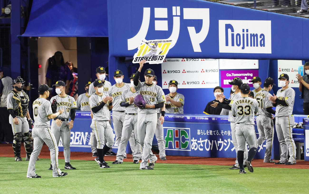 DeNA対阪神　4回裏DeNA2死、宮崎を空振り三振に仕留め、通算1000奪三振を達成しボードを掲げる藤浪（中央）（撮影・足立雅史）