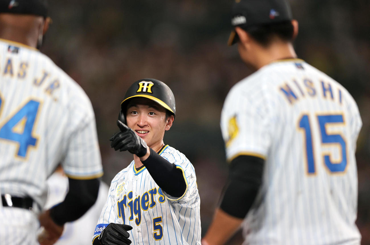 阪神対中日　4回裏阪神2死一、二塁、原口文仁の左前適時打で先制生還した近本光司（中央）は出迎えにポーズする（撮影・上山淳一）