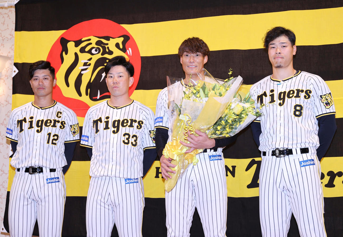 記者会見を終えた阪神糸井（左から3人目）は花束を手に写真に納まる、左から坂本、糸原、1人おいて佐藤輝（撮影・上山淳一）