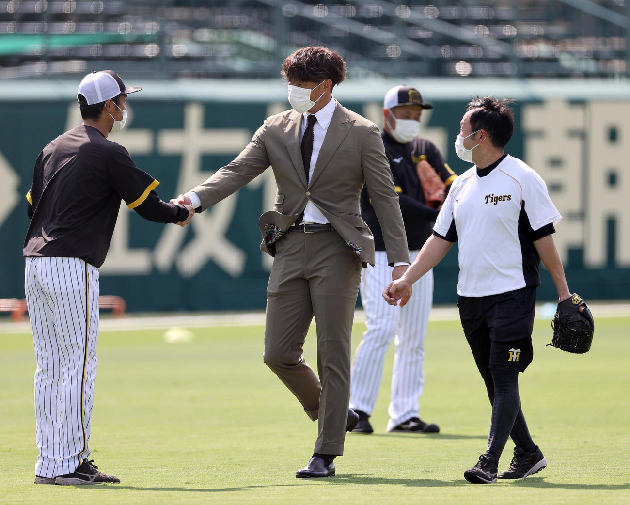 引退会見を終えた阪神糸井（左から2人目）はスーツ姿で甲子園球場に現れ関係者にあいさつする（撮影・上山淳一）