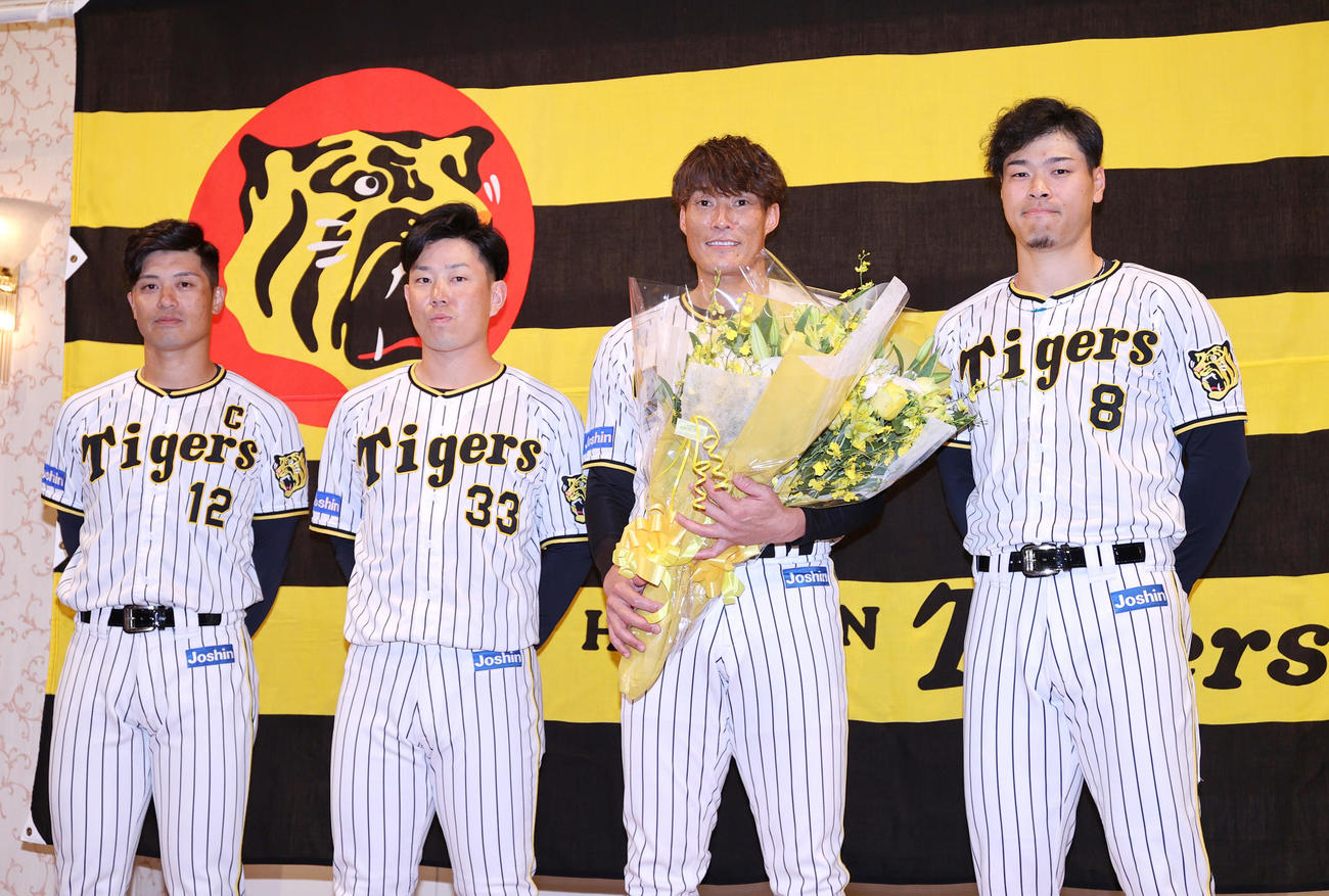 記者会見を終えた阪神糸井（左から3人目）は花束を手に写真に納まる、左から坂本、糸原、ひとりおいて佐藤輝（撮影・上山淳一）