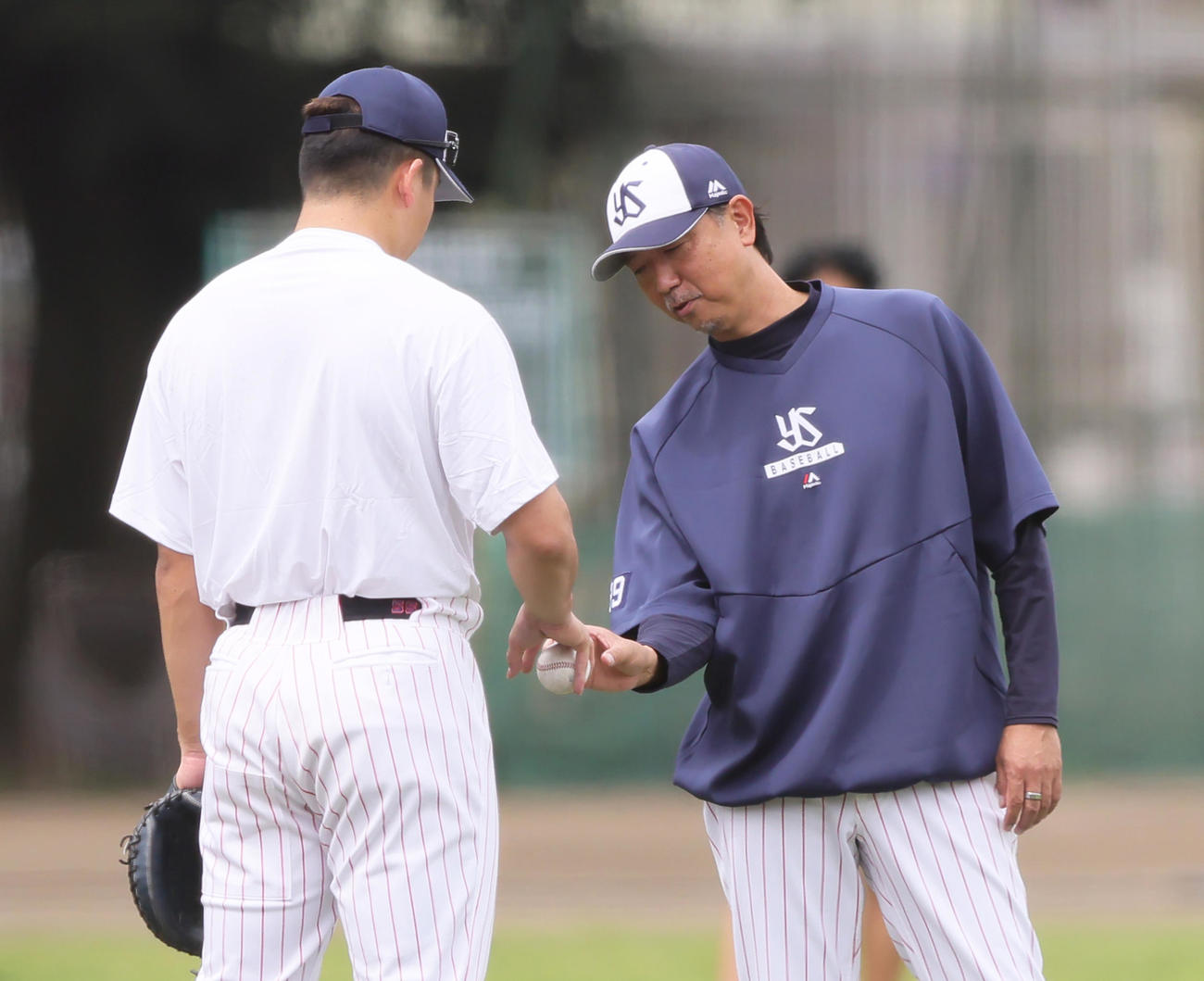 ヤクルト伊藤コーチ（右）に球の握りを教えてもらう村上（撮影・足立雅史）