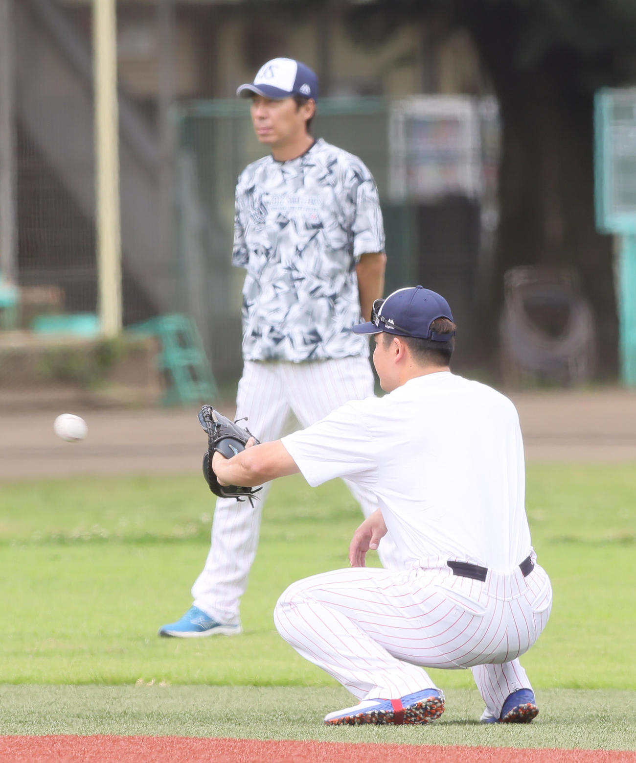 ヤクルト村上（手前）は嶋のミットを手に練習する。後方は高津監督（撮影・足立雅史）
