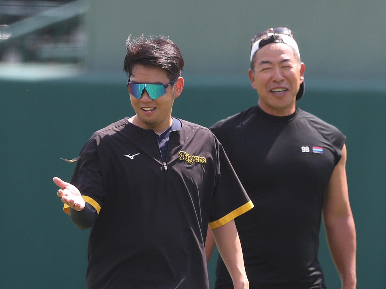 西勇の手のひらの上を飛ぶとんぼ。右は井上コーチ（撮影・白石智彦）