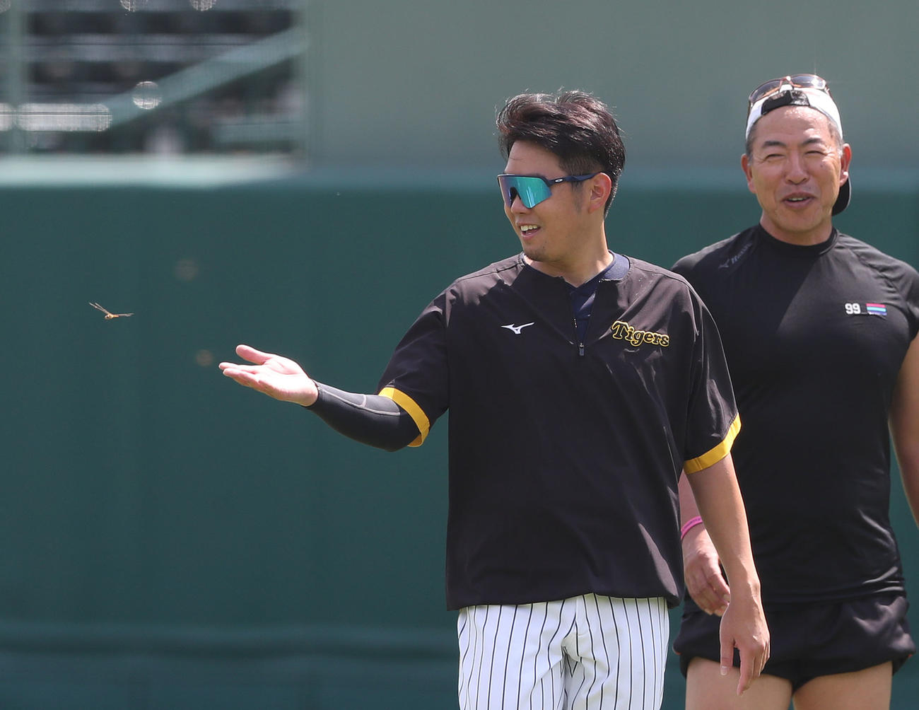 西勇の手のひらの上を飛び去るとんぼ。右は井上コーチ（撮影・白石智彦）
