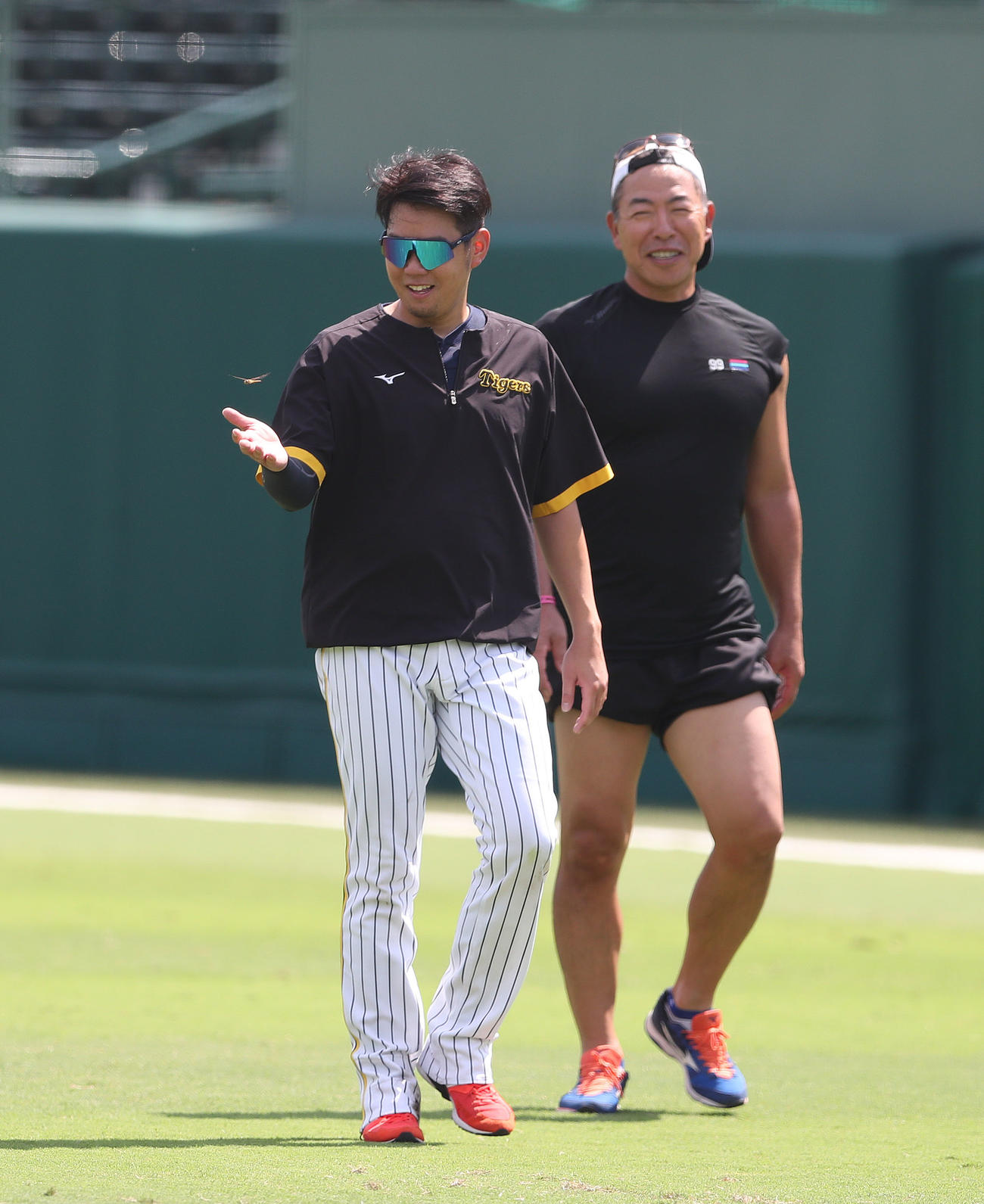 西勇の手のひらの上を飛ぶとんぼ。右は井上コーチ（撮影・白石智彦）