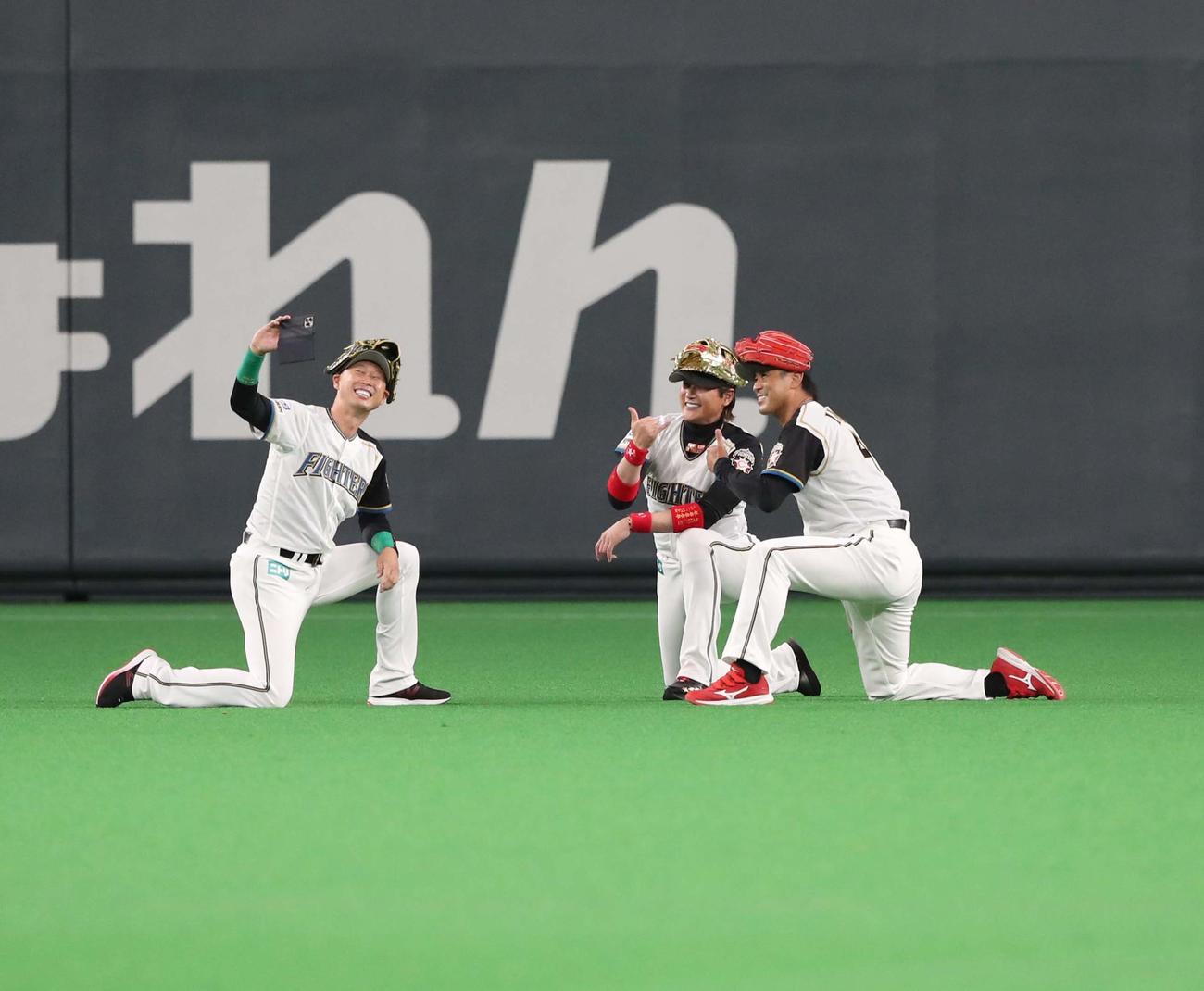 日本ハム対ロッテ　ファイターズレジェンドメモリアルピッチセレモニーで、当時恒例のポーズをとり自撮りする左から森本氏、新庄監督、稲葉GM（撮影。黒川智章）
