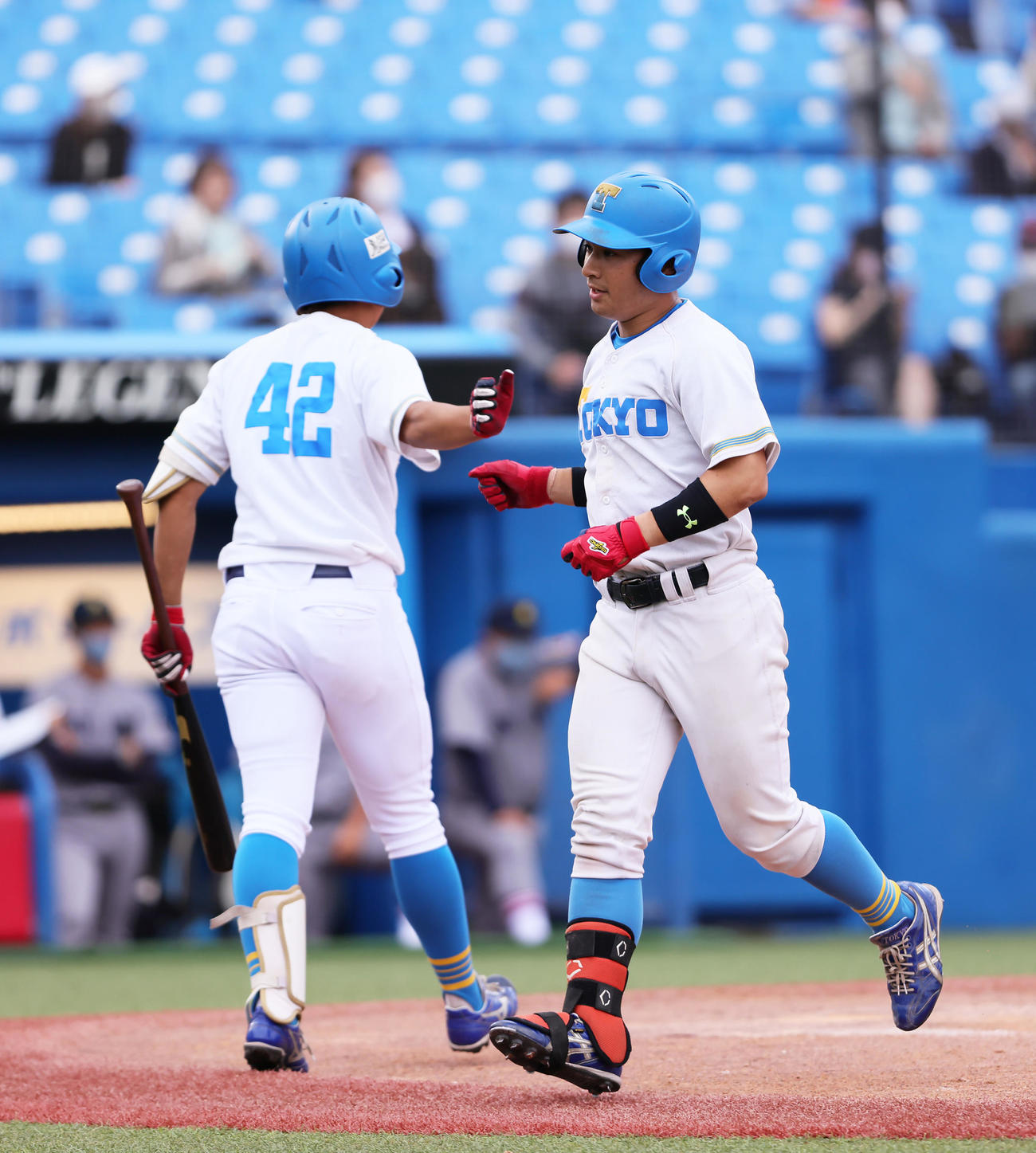 慶大対東大　4回裏東大1死、阿久津（右）は右越え本塁打を放ちタッチを交わす（撮影・足立雅史）