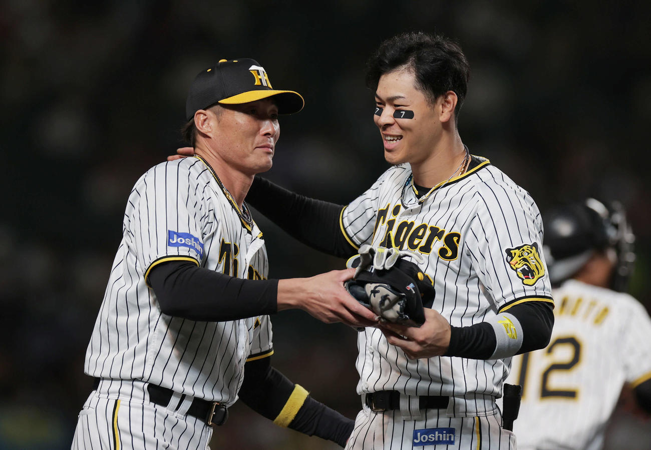 阪神対広島　1回裏の攻撃を終え、迎えた阪神糸井からグラブと帽子を受け取り笑顔を見せる佐藤輝（撮影・前田充）