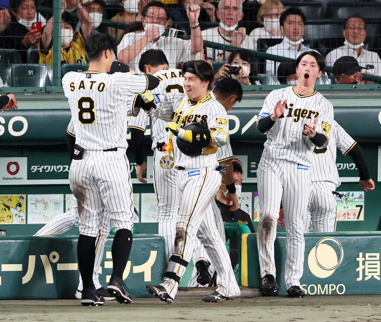 阪神対広島　6回裏阪神2死、左越えソロ本塁打を放った梅野は佐藤輝（左）、近本らナインと笑顔でタッチ（撮影・加藤哉）